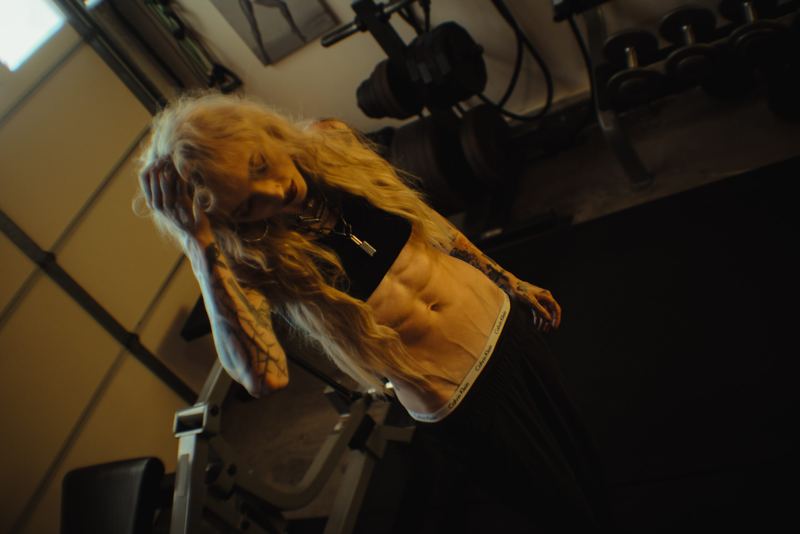 Female fitness coach with visible abdominal definition in a gym, representing precision-based body recomposition coaching.