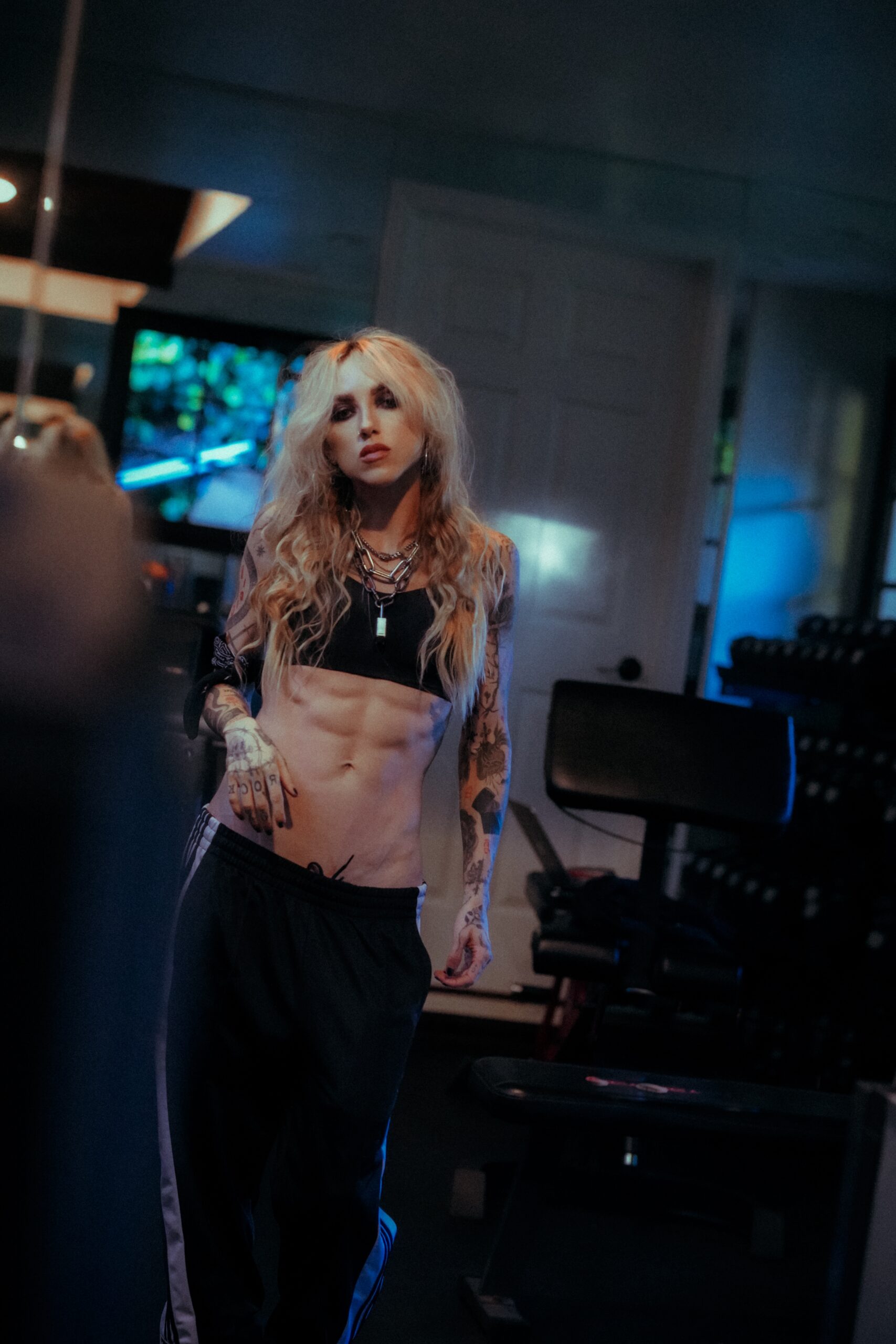 Female physique coach with visible abdominal definition demonstrating camera-ready conditioning in a private training studio.